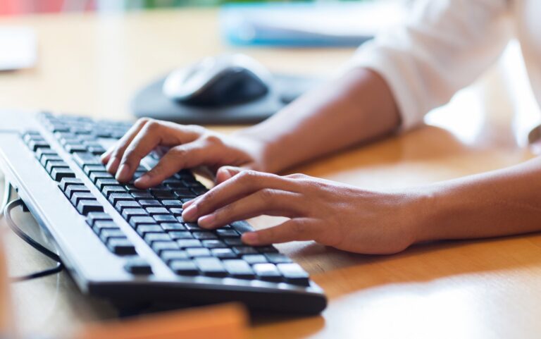 Hands typing website content on a keyboard