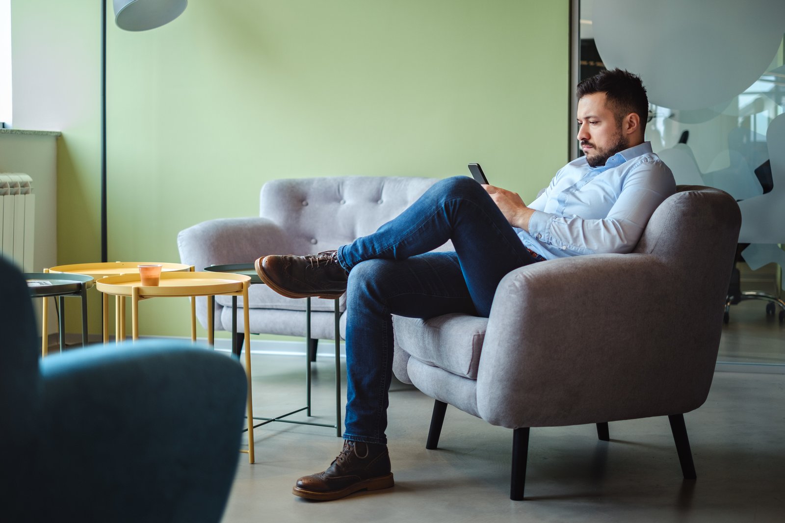 Man in an armchair browsing job listings on his phone