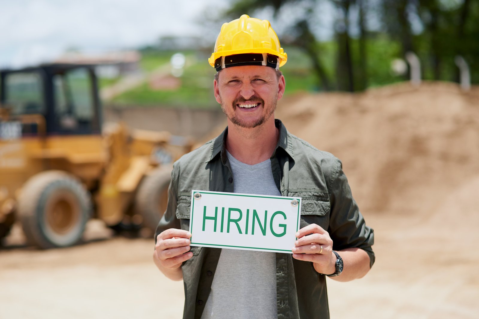 Contractor holding a hiring sign at a job site