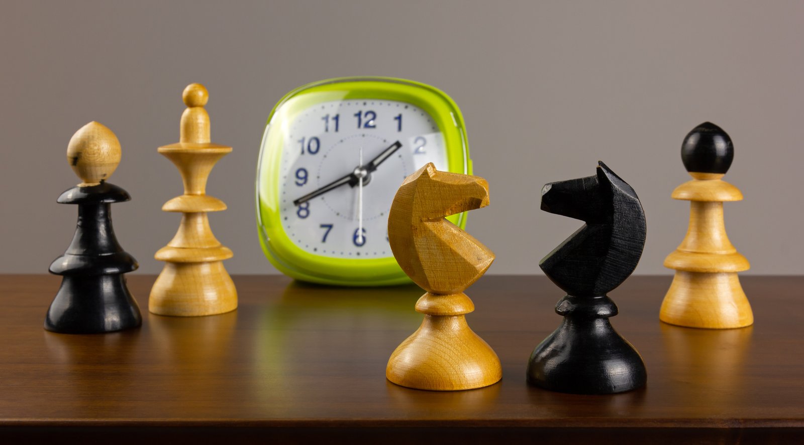 Two sets of chess pieces facing off across a chess clock