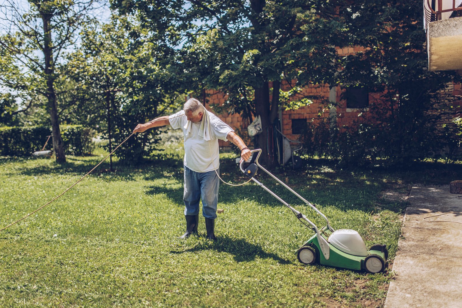 Landscaper mowing a lawn, one of the many trades that run on Jobber