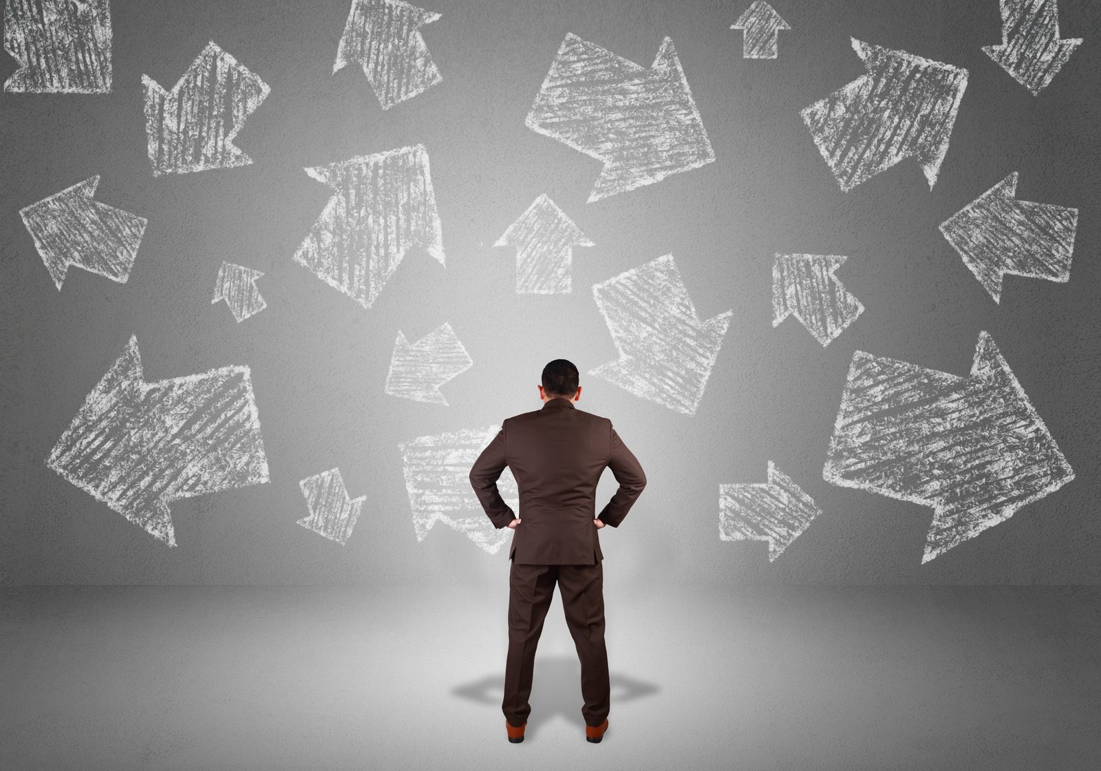 Businessman facing chalk arrows pointing in many directions, weighing his options